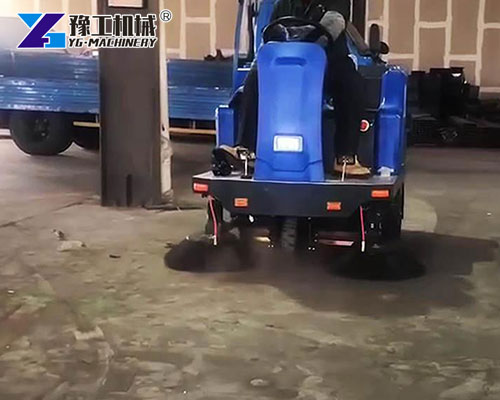 Factory worker driving ride-on floor sweeper