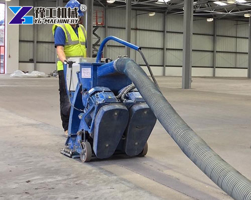 Worker using floor shot blaster on warehouse