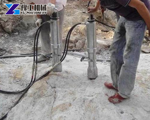 Workers operating hydraulic splitter for quarry blocks